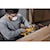 Zoomed in photo of user sanding the side of a wooden kitchen cabinet with the DCW220B and the DCB205 battery 