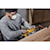 Zoomed in photo of user sanding the side of a wooden kitchen cabinet with the DCW220B and the DCBP520 battery 