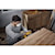 User sanding the side of a wooden kitchen cabinet with the DCW220B and the DCBP520 battery 