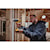 ATOMIC Brushless Compact Cordless half inch Hammer drill driver  is being used by a person to drill  wooden plank.